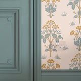 Clear white double socket painted pastel green fixed to wall with pastel green and orange floral wallpaper next to pastel green wooden door 